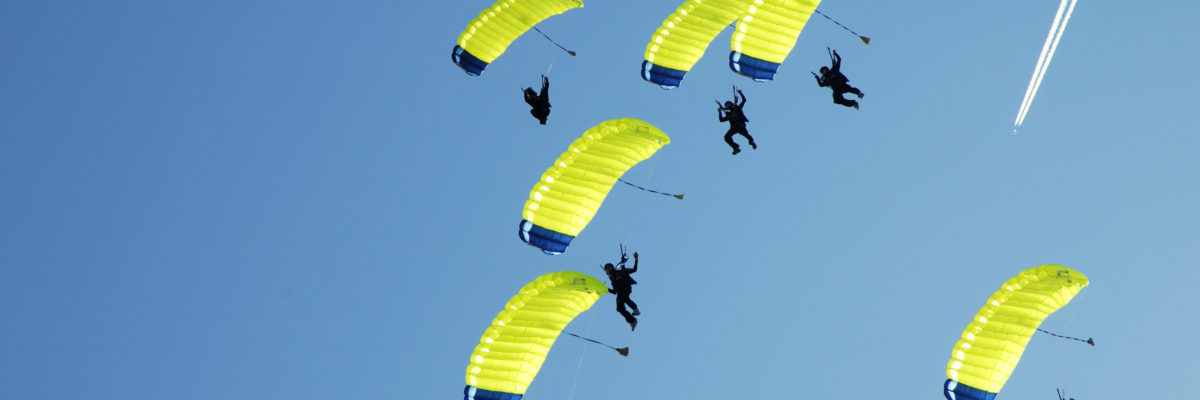 A collection of jumpers parachuting down together, gracefully